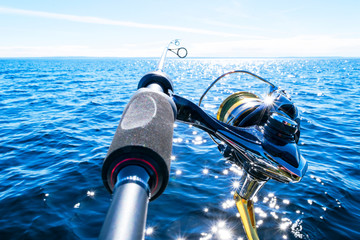 Fishing rod spinning with the line close-up. Fishing rod in rod holder in fishing boat due the...