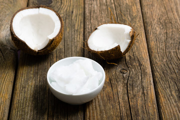 pile of rigid coconut oil on china dish and broken coconut shells, old wood table