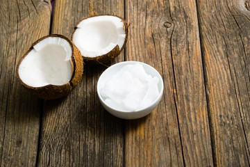 pile of rigid coconut oil on china dish and broken coconut shells, old wood table