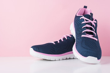 Pair of female sport shoes on a pink background, close up