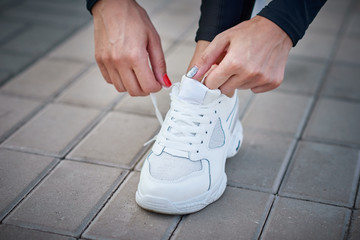 Woman get ready for run. Female hands tying shoelaces on a sport sneakers