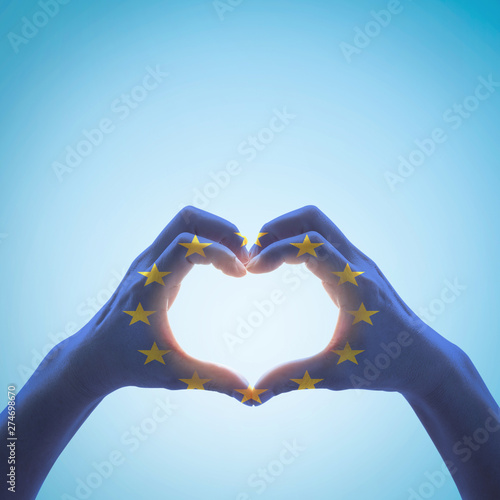 European Union flag pattern on people hands in heart shape on blue sky