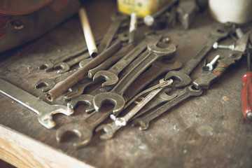 Grunge, vintage wooden workbench with rustic old metal wrenches of different measures lying. Old...