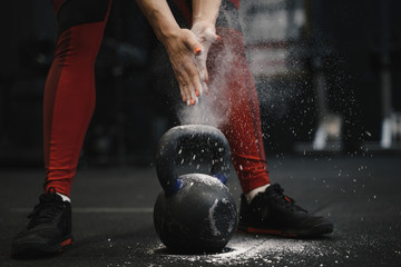 Closeup of crossfit female athlete claping hands with cloud of dust while magnesia protection.