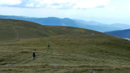 Fototapeta na wymiar People hiking on alpine meadows on mountains, withered grass but deep blue sky, Carpathian mountain chains