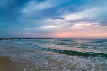 Twilight time at the beach in Netanya, Israel, Mediterranean sea. Overcast sky, foam and waves.