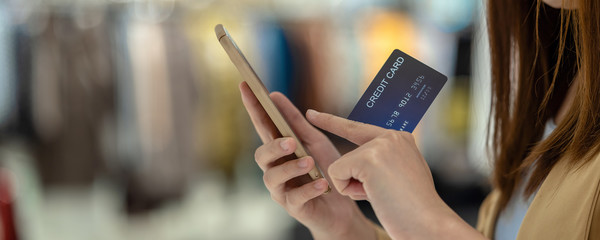 banner of Asian woman using credit card with mobile phone for online shopping in department store over the clothes shop store, technology money wallet and online payment concept, credit card mockup