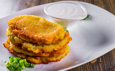 potato pancakes with sour cream in a plate on wooden table