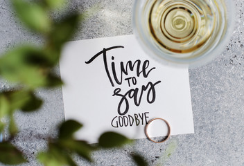 Time to say goodbye. The inscription on a white paper sheet. White wine in a glass glass. Gold engagement ring. Concept - deterioration of relations between people