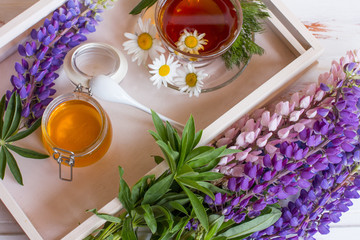 Tray with a Cup of herbal black tea and a jar of honey. The scent of flowers is therapeutic.
