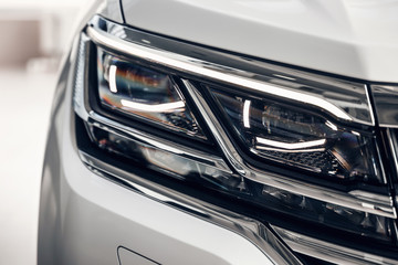 Close-up headlights of a modern white color car. Detail on the front light of a car. Modern and...
