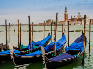 Fototapeta na wymiar Row of gondolas moored on the lagoon in front of San Giorgio Maggiore island, Venice, Italy
