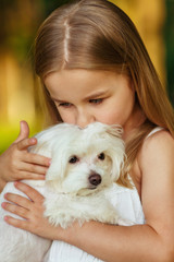 Little girl with a maltese puppy, outdoor summer