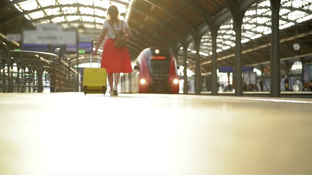 Young Caucasian Woman With Suitcase Running To Catch The Train In Before It Leaves The Station Without Her.