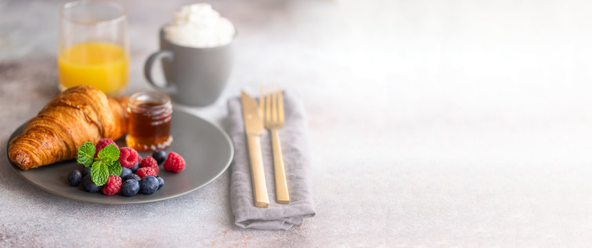 French croissant served with  fresh berries and syrup, cup of coffee and orange juice. Continental breakfast in the hotel background. Good morning concept.