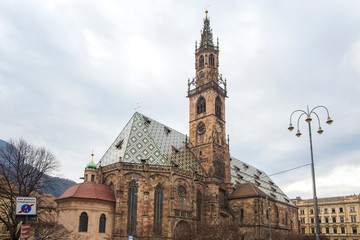 Fototapeta premium Bolzano, South Tyrol, Italy - January 27, 2019: Piazza Walther with tourists at the Monument to the poet Walther von der Vogelweide in the Old town of Bolzano in South Tyrol. Cathedral of Bolzano