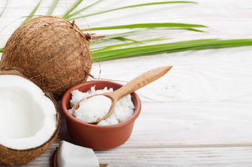 Background of coconut, coconut shell, oil in clay bowl and spoon on white wooden table