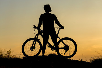 Plakat Cyclist in shorts and jersey on a modern carbon hardtail bike with an air suspension fork rides off-road on the orange-red hills at sunset evening in summer 