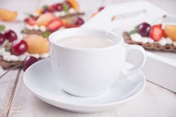 Cup of tea and crisp bread with creme cheese, fruit and berries