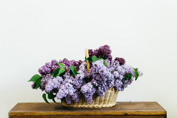 Violet lilac flowers bunch in a basket on wooden table
