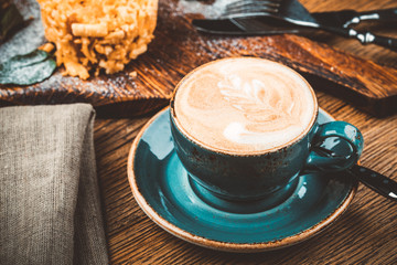 Cappuccino Cup with latte on wooden background. Beautiful foam, green ceramic Cup.