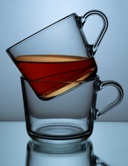 Two glass transparent cups with tea on a black and blue background