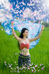 Beautiful woman standing with her blue cover silk among flower blossom field.