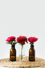 Red roses in glass vases on a wicker napkin on white background