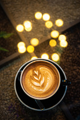 Latte art coffee with bokeh of lights on  table, Dark tone