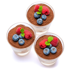 Classic tiramisu dessert with blueberries and raspberries in a glass isolated on a white background with clipping path