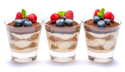 Classic tiramisu dessert with blueberries and raspberries in a glass isolated on a white background with clipping path