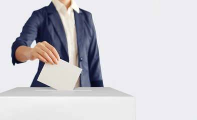 Voting. Woman putting a ballot into a voting box.