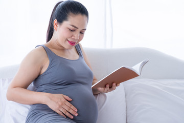 Pregnant woman holding a book and put her hand on belly. Mental health care and pregnancy.