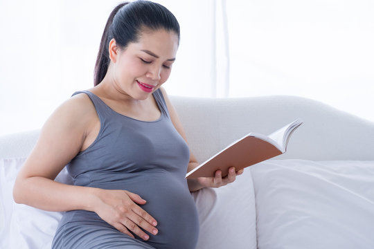 Pregnant woman holding a book and put her hand on belly. Mental health care and pregnancy. - Powered by Adobe