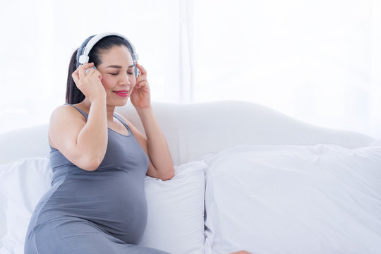 Pregnant woman listening to music on the bed. Mental health care and pregnancy.