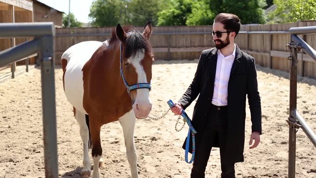Handsome man in a suit standing by the horse