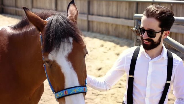 Handsome man standing by the horse