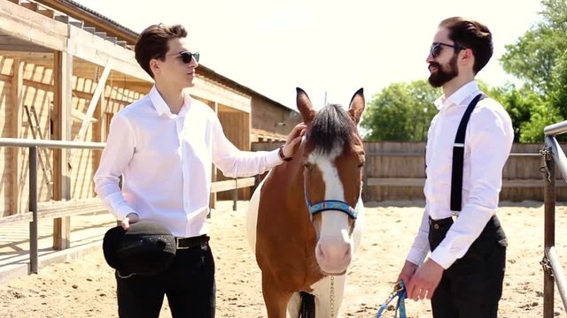 two businessmen standing near a horse