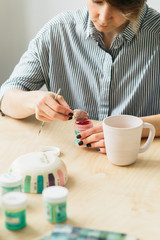 the pottery girl holds in hands a mug to paint the ornament