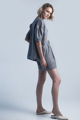 Fashion portrait of blonde female model on grey background. stylish green clothes and accessories....