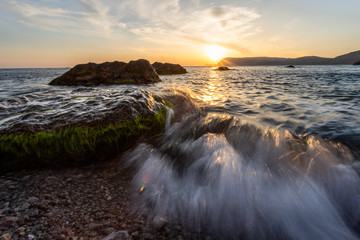 waves hits rocks during sunset. image contain soft focus and blue due to slow shutter