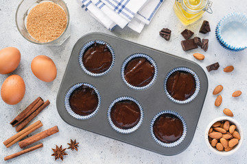 Homemade cupcakes or muffins dough in baking tin. Preparation of sweet chocolate pastry. Baking ingredients and utensils background, top view