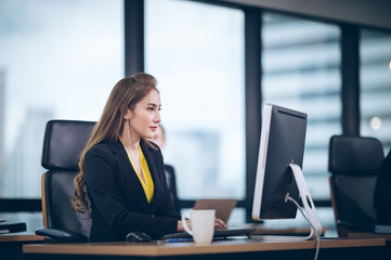 Obraz premium Operators use a computer on a desk in an office, adult business woman sitting on a desk in a business organization
