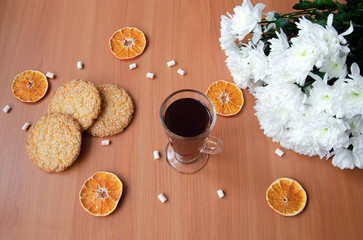 glass cup with tea, cookies, candy and white chrysanthemum flowers