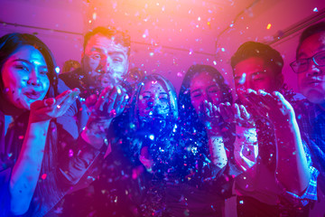 People on a party in the nightclub.group of friends celebrate party and throwing confetti while enjoying home Young company celebrates birthday with a cocktail in hand. - obrazy, fototapety, plakaty