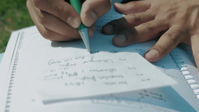 Close-Up,the Hands of an Indian Student with A Pen Recorded on a Sheet of Paper Notes from the Book