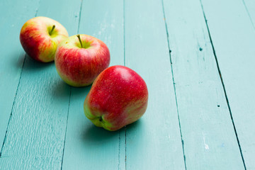 three apples on blue wooden background
