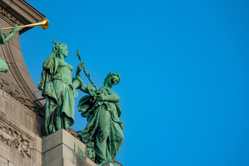 Close up of green statues at parc du cinquantenaire against blue sky