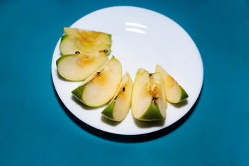 fresh apple fruits pieces on a plate on blue background