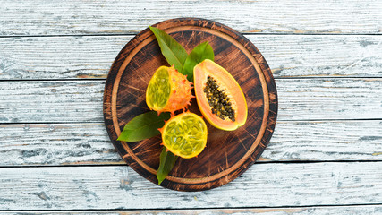 Kiwano and papaya on a wooden board. Top view. Free space for text.
